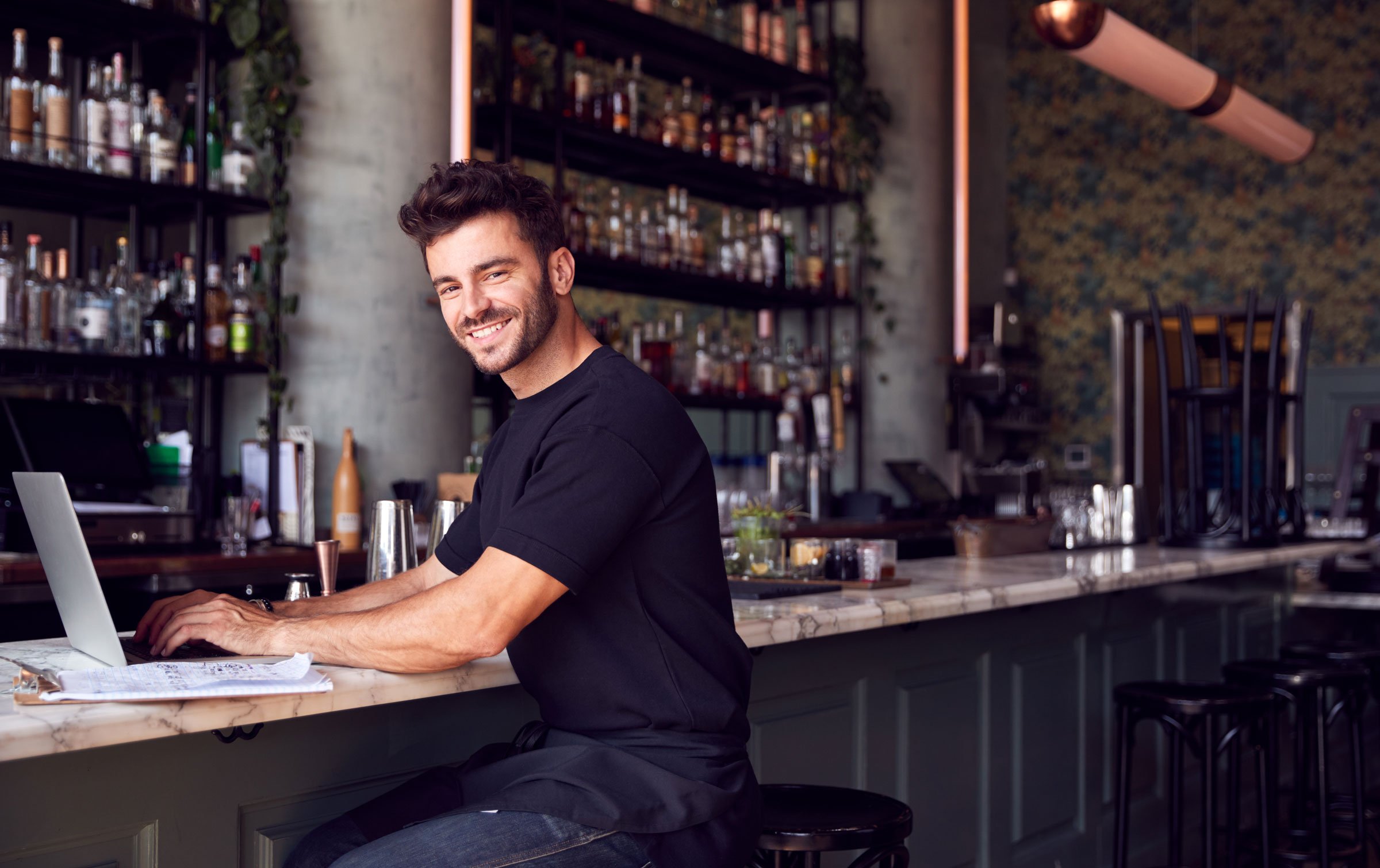 portrait-of-male-owner-of-restaurant-bar-sitting-a-ZAC5RQD